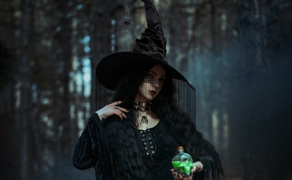 Woman in a dark witch costume holding a green potion bottle in a forest setting